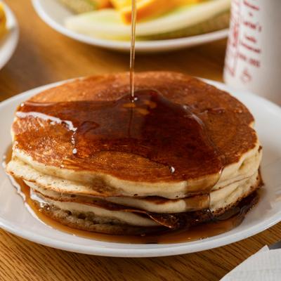 Stack of buttermilk pancakes being drizzled with syrup.
