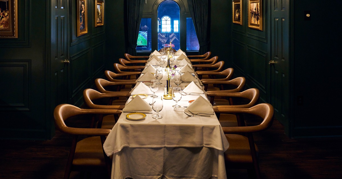 Long banquet table prepared for guests with linens and glassware