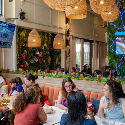 Patrons dining in a restaurant featuring wicker pendant lighting and a vertical garden wall.