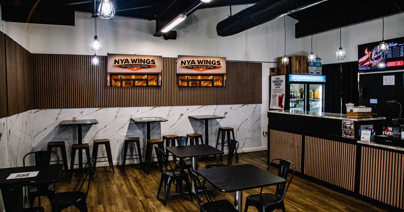 Interior of a modern restaurant with wood and marble decor featuring tables, stools