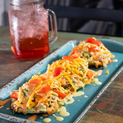 Tostones topped with cheddar cheese, red bell peppers, and garlic-cilantro aioli.