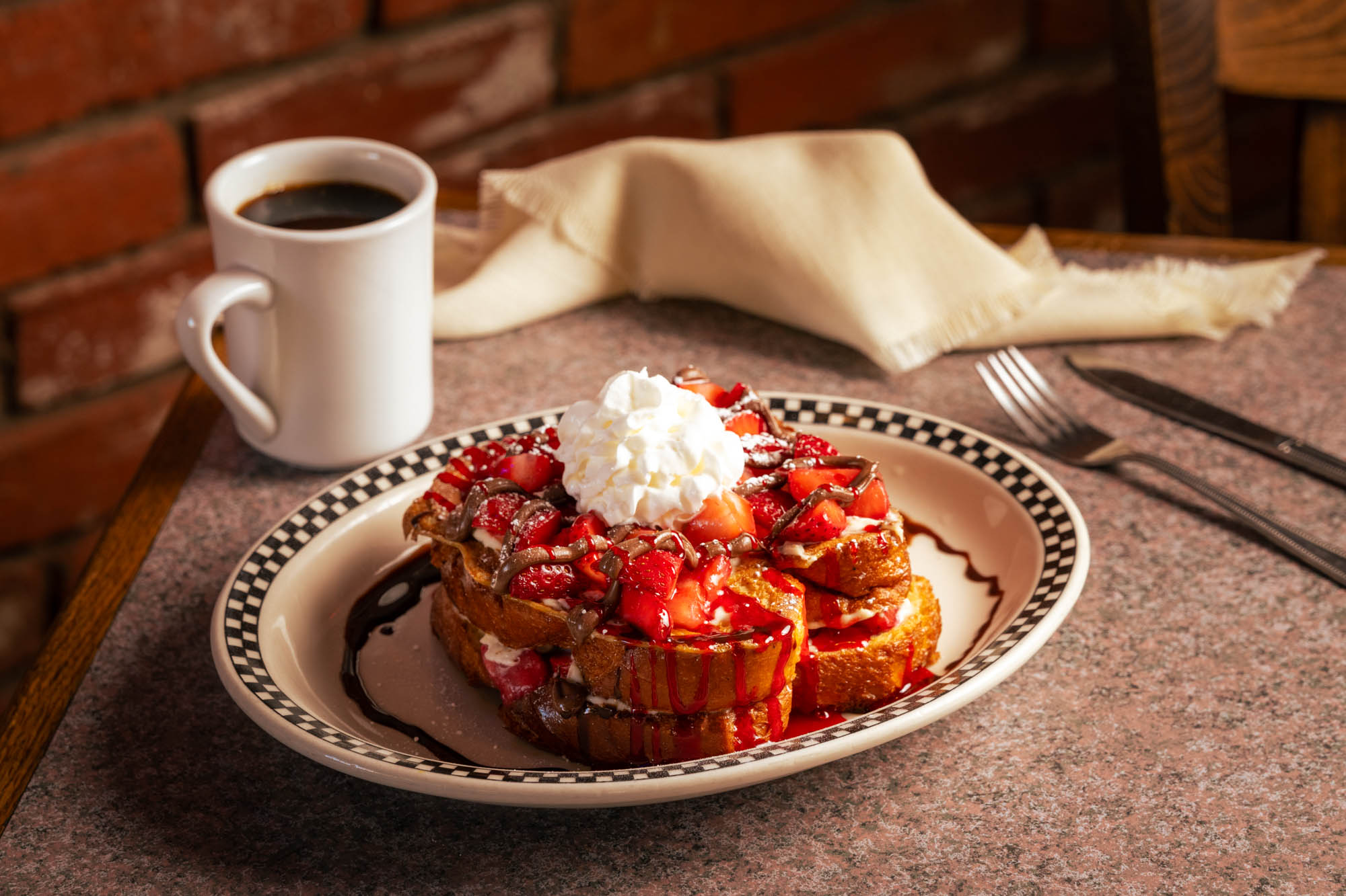Strawberry French toast with chocolate drizzle, whipped cream, and black coffee