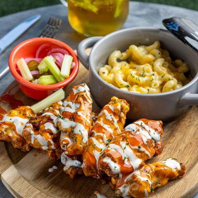 Buffalo wings accompanied by mac and cheese and celery sticks.