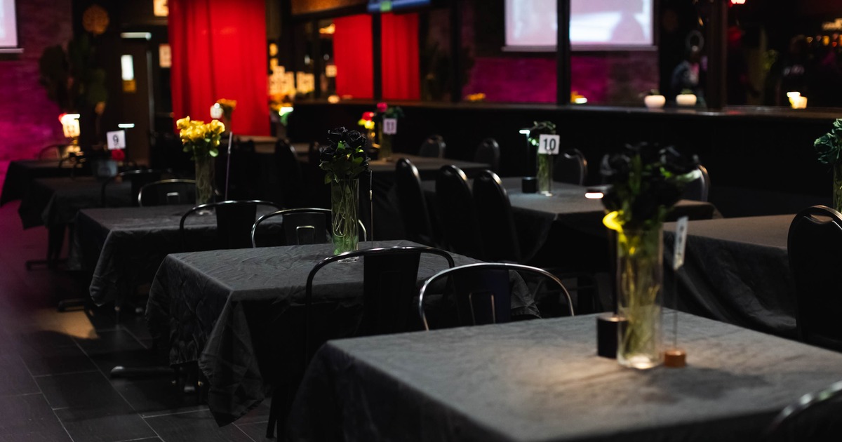 Interior, dining area, black cloth tables with flower vases and black metal chairs, closeup