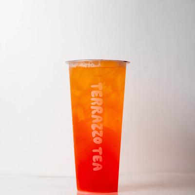 A tall cup of vibrant orange and red iced tea labeled 