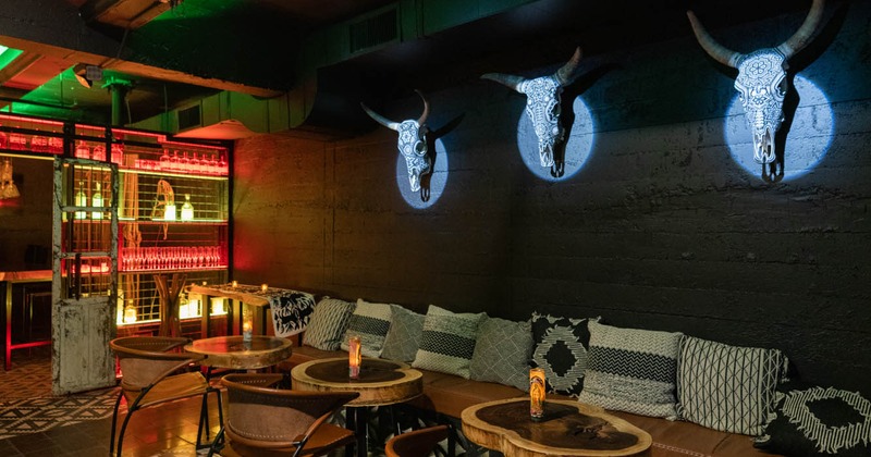Interior, seating with pillows and tables by a wall decorated with ornamented  cow skulls