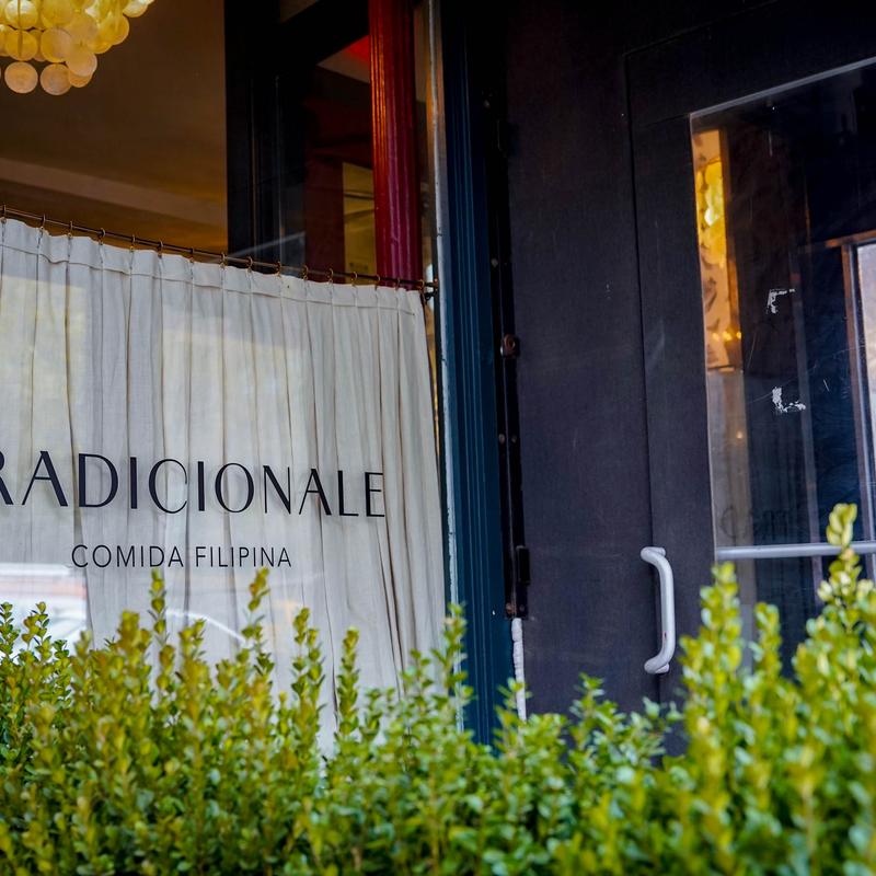 Tradicionale Comida Filipina restaurant entrance with signage, white curtain, and greenery.