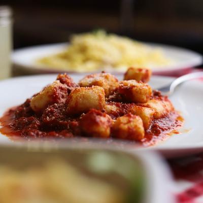 Plate of gnochi with Chicken Alfredo pasta in the background.