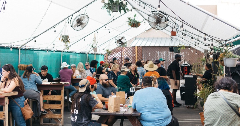 Photo of an outside beer garden teeming with customers. Photo Credit: Kat Hanegraaf Photography