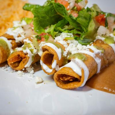 Chicken flautas, served with guacamole, green salsa, lettuce, pico, sour cream, rice, and beans.