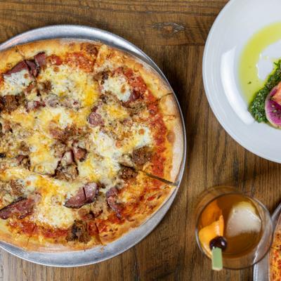 Pizza with tomato, sausage, salami, pork, duck, and cheeses.