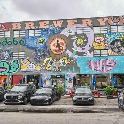 View of the brewery building with extensive graffiti art covering its exterior walls.