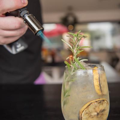 Gin and Tonic cocktail, with burning rosemary garnish.