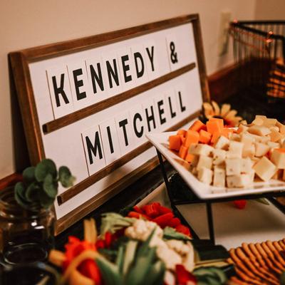 A close up of a sign with wedding couple's names, placed on a grazing table.