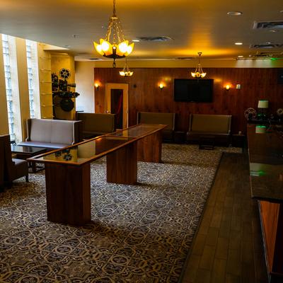 A long, elegantly designed room with a bar, booths, and coffee tables.