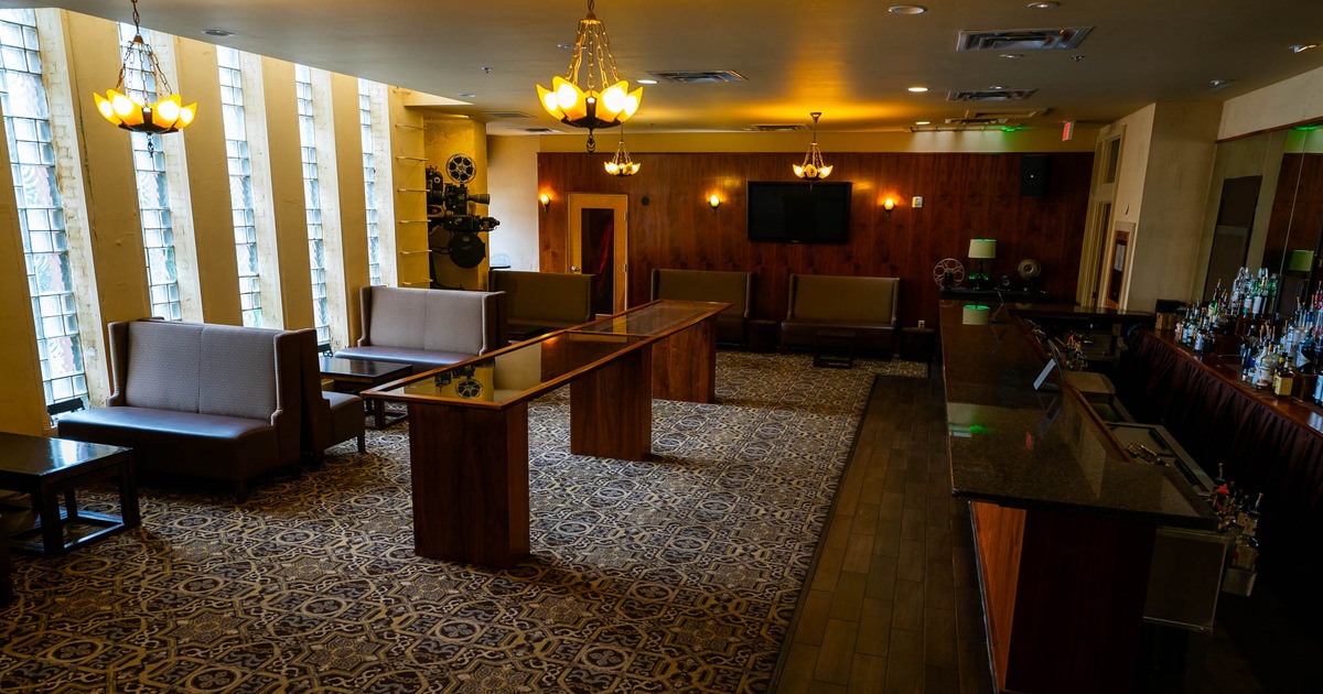 A long, elegantly designed room with a bar, booths, and coffee tables