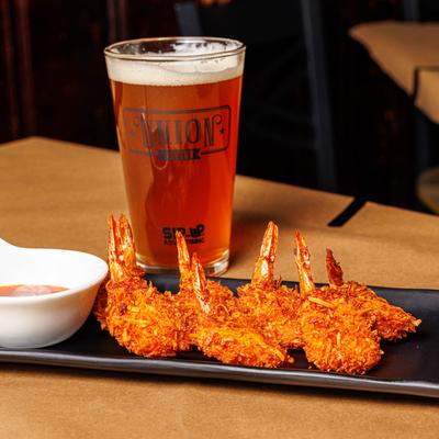 Coconut Shrimp served with sweet chili sauce and a glass of beer.
