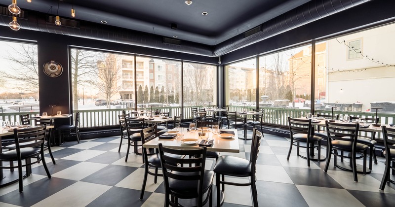 Interior seating area with large windows, checkered floor, and set tables