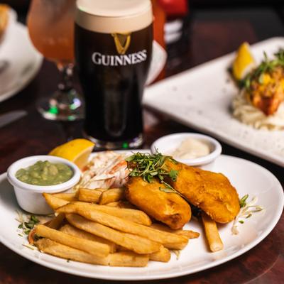 Fish and chips with mushy peas, coleslaw, tartar sauce, and a pint of Guinness.