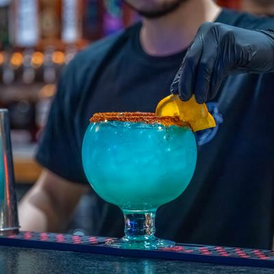 Bartender garnishing a blue cocktail.