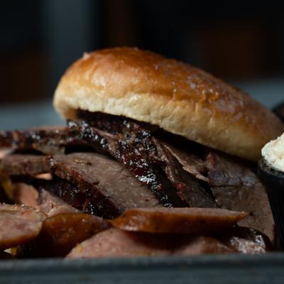 Beef Brisket Sandwich with cut sausage on the side.