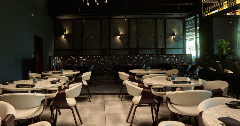Interior, dining area, round tables with comfy chairs, tile flooring, dimmed lighting