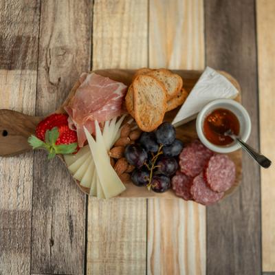 Charcuterie board with meats, cheeses, sauce and fruit.