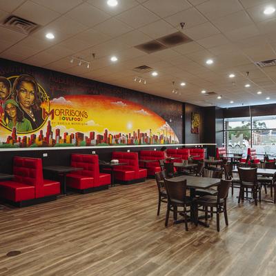 Interior, dining tables and chairs, booths by a wall with mural.