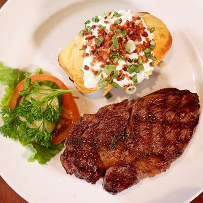 Grilled ribeye steak, loaded baked potato, and veggies.
