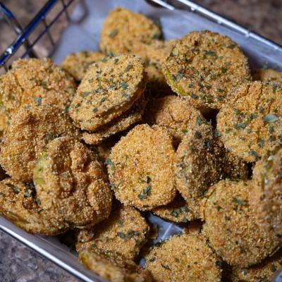 Fried pickles with herb seasoning in a metal basket.