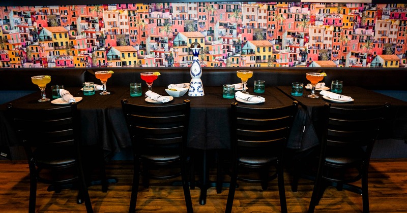 Interior, banquette seating by a wall with served cocktail drinks and tableware