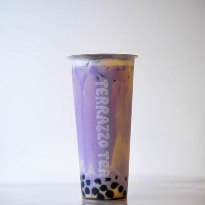 A tall cup of bubble tea with purple and yellow swirls..