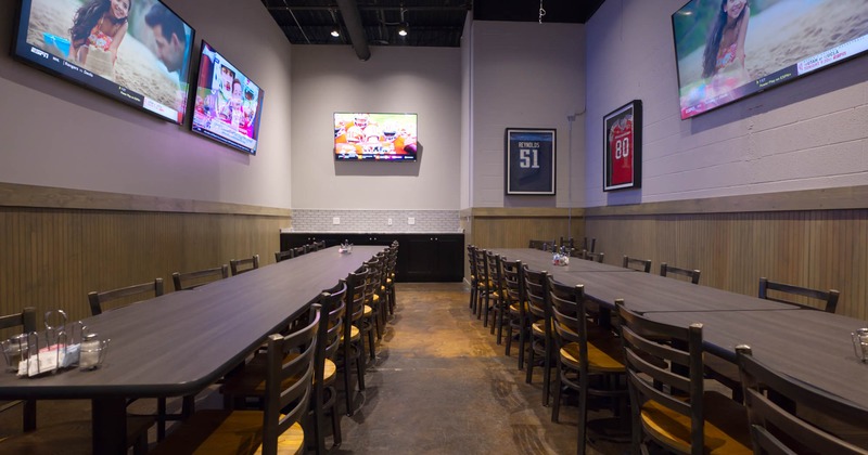 Interior, long dining tables and chairs, TVs on the walls