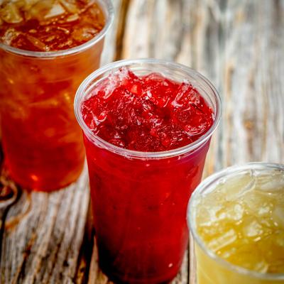 Cups of iced tea lined on a rustic wooden table.