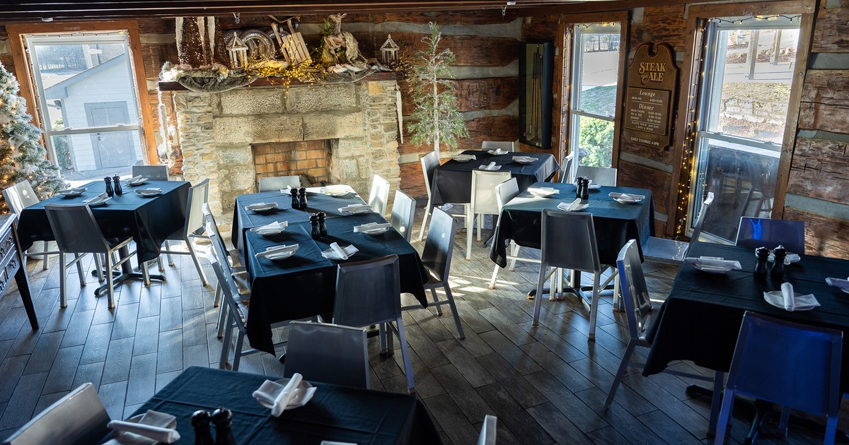 A room featuring wall fireplace, tables set for dining and Christmas decor