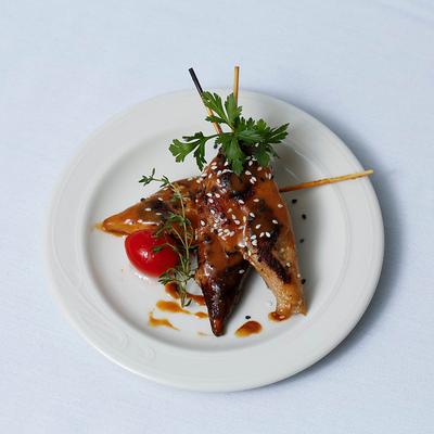 Grilled chicken skewers with sesame seeds, sauce, herbs and a cherry tomato.