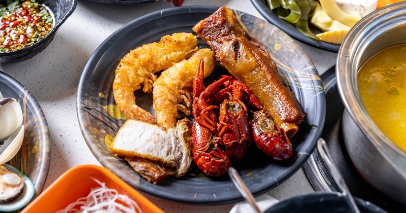 Plate of hot pot ingredients, including fried prawns, crawfish, and braised pork
