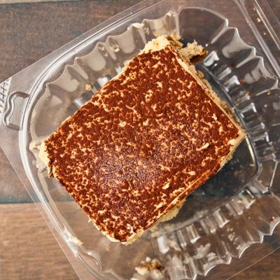 Tiramisu dusted with cocoa powder and served in a take-out container.