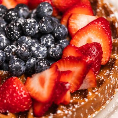 Waffle topped with sliced strawberries abd blueberries, close-up.