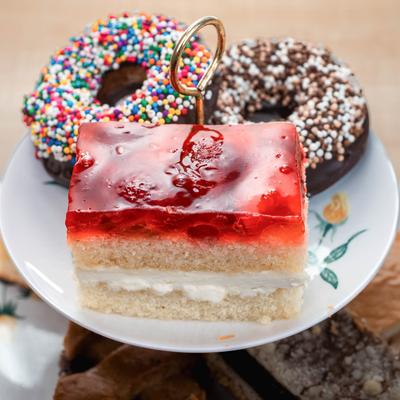 Layered dessert display with a slice of strawberry cake, colorful donut, and chocolate donut.