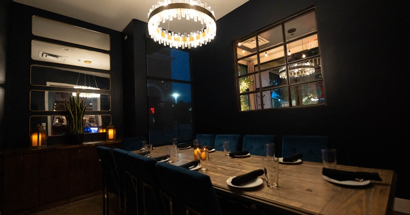 A dining room with a wooden table, blue chairs, and a modern chandelier above