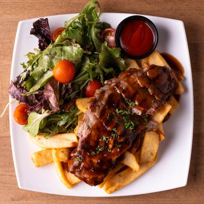 Savory ribs covered in sauce, served with fries and a mixed garden salad.