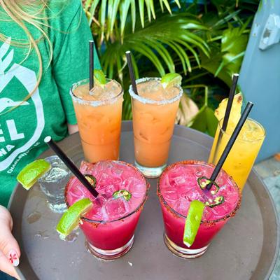 A tray of vibrant cocktails, orange, yellow, and pink, and a clear shot.