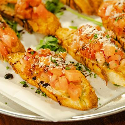 Bruschetta with tomatoes, red onion, garlic, pesto, and extra virgin olive oil.