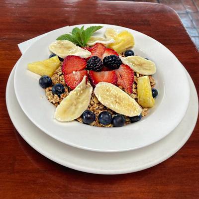 Granola topped with blueberries, banana, and pineapple, garnished with a mint leaf.