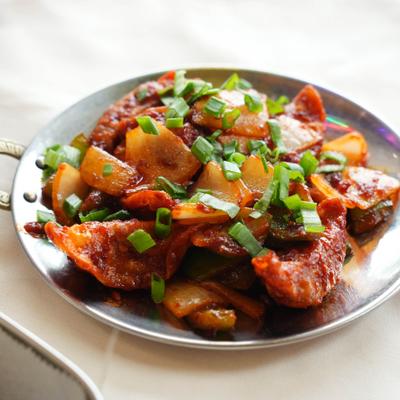 Chili dumplings served with onion and garnished with green onion.
