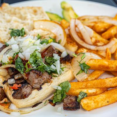 Steak sandwich served alongside fries, rice and beans.