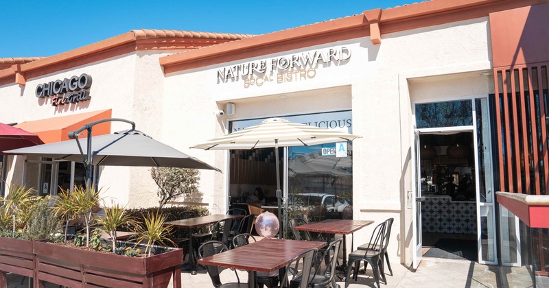 Outdoor view of a café with patio tables and black chairs