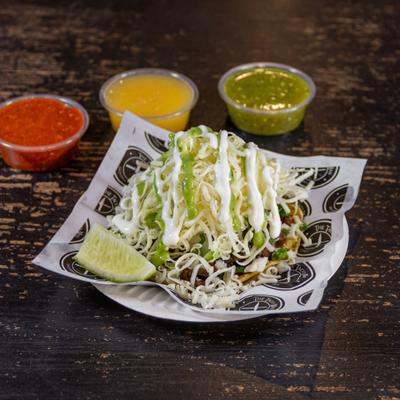 Taco with cabbage, onion, cilantro, shredded cheese, avocado sauce, and sour cream.