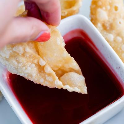 Hand dipping fried wonton, closeup